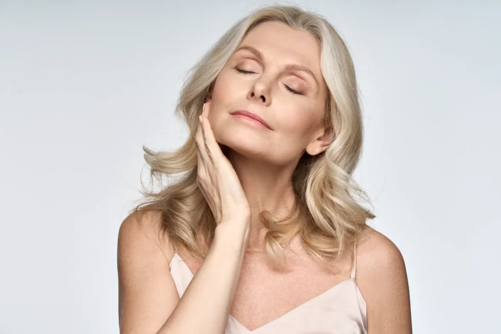 Mature woman with eyes closed touching her face